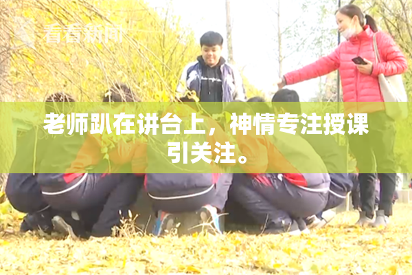 老师趴在讲台上，神情专注授课引关注。